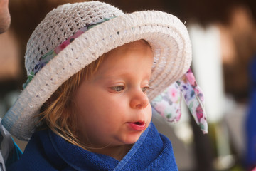 Close-up Portrait of Cute Adorable Two Years Old Toddler Girl with Blonde Hair and Big Blue Eyes, in White Big Summer Hat, Sitting at the Pool Area in Cancun Resort in Mexico, March 2018
