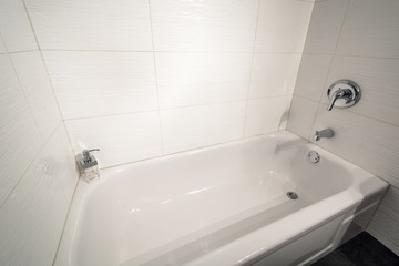 White bathtub in a tiled bathroom. Interior design.