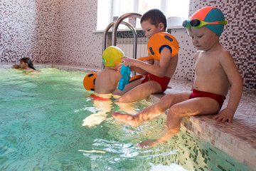 Obraz na płótnie Canvas Funny preschoolers, boys and girl in bright bathing suits and swimming goggles, swim, dive in home pool. Happy children, twins, boy and girl have fun together. Concept of childhood, health, friendship