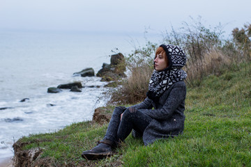 Young woman in grey coat  against the autumn sea background 