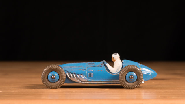 Metal retro toy race car on wooden table with black background