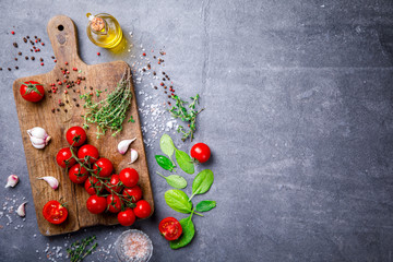 Organic vegetarian ingredients, olive oil and seasoning on rustic wooden cutting board over dark vintage background 