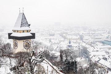 Snowy Uhrturm clocktower landmark on hill Schlossberg and city Graz