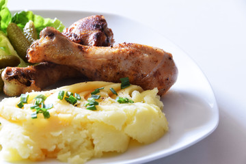 chicken drumsticks fried in a pan with potato puree with chives and fresh salad with mini cucumbers...