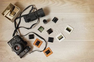 Photo concept. Old camera shots film lens photos on wooden background top view.
