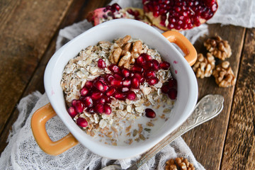 Tasty homemade Breakfast: oatmeal with pomegranate and nuts on natural wooden background rustic. The concept of a healthy diet, a high-carbon Breakfast.