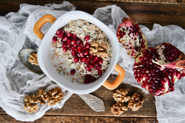 Tasty homemade Breakfast: oatmeal with pomegranate and nuts on natural wooden background rustic. The concept of a healthy diet, a high-carbon Breakfast.