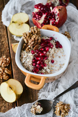 Breakfast: granola with pomegranate and walnuts and green Apple on natural wooden background rustic. The concept of healthy and high-carbon nutrition.