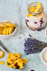 Breakfast in a glass jar: homemade granola, banana, fresh berries, yogurt on a light textile background with a bouquet of lavender. The concept of healthy eating, high-carbon Breakfast.