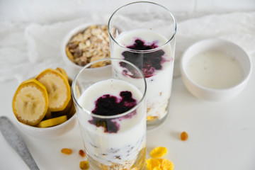 Breakfast in glass Cup: homemade granola, banana, fresh berries, yogurt on white background. The concept of healthy eating, high-carbon Breakfast.