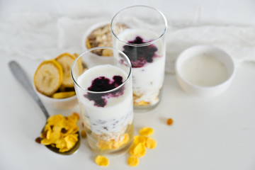 Breakfast in glass Cup: homemade granola, banana, fresh berries, yogurt on white background. The concept of healthy eating, high-carbon Breakfast.
