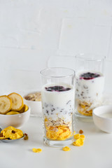 Breakfast in glass Cup: homemade granola, banana, fresh berries, yogurt on white background. The concept of healthy eating, high-carbon Breakfast.