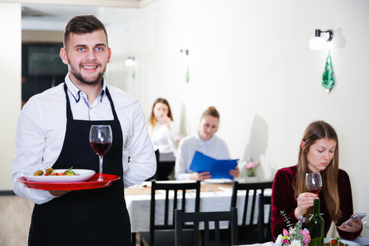 Portrait of welcoming waiter who is standing in restaurante
