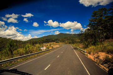 Highway Bend against Hilly Country land Blue Cloudy Sky