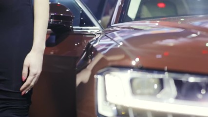 close up view of a headlamp of a new elegant car on the auto exhibition show and woman hand on background / pasanger business sale showroom prestige lifestyle shiny lamp light tuned detail transport