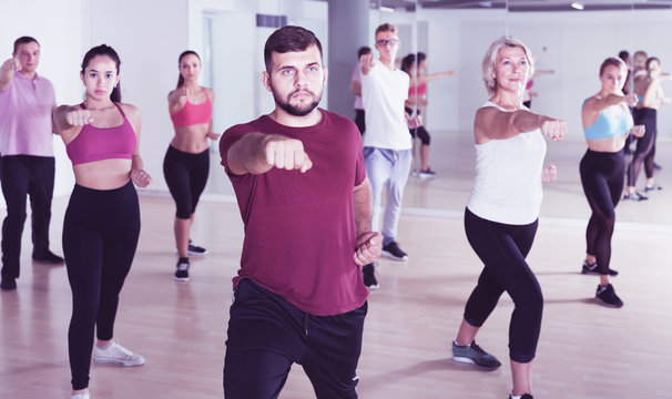 active men women posing in fitness studio