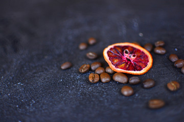 Beautiful and tasty background for design. Dried red orange slices with a coffee beans on a stone background. Cuisine wallpaper.