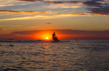 silhouette of a man on a jet ski in the sun