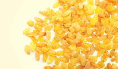 Placer of raisins on the light yellow background. Large dried grapes.