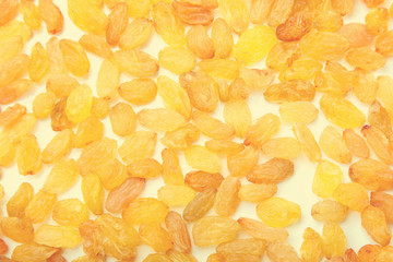 Placer of raisins on the light yellow background. Large dried grapes.