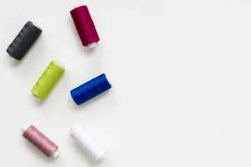 Colored thread coils on white background, sewing, place for text