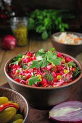 Vinaigrette salad with boiled vegetables, pickled cucumbers, sauerkraut and canned green peas in a clay bowl. Traditional Russian snack. Vegetarian food.