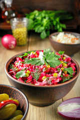 Vinaigrette salad with boiled vegetables, pickled cucumbers, sauerkraut and canned green peas in a clay bowl. Traditional Russian snack. Vegetarian food.