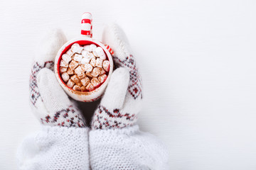 Female hands holding hot chocolate with marshmallow and cinnamon. Warming holiday drink on a white background.  Warm Christmas.CocoaTop view with Copy space