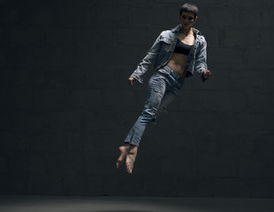 Girl in jeanswear jumping gracefully in the dark