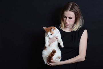 Blonde girl in black dress holding a white-red cat