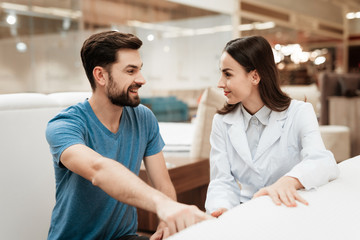 Fototapeta premium Confident man with beard communicates with beautiful girl consultant in mattress store.