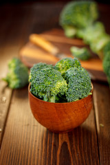 Broccoli crowns in a wooden bowl over table.