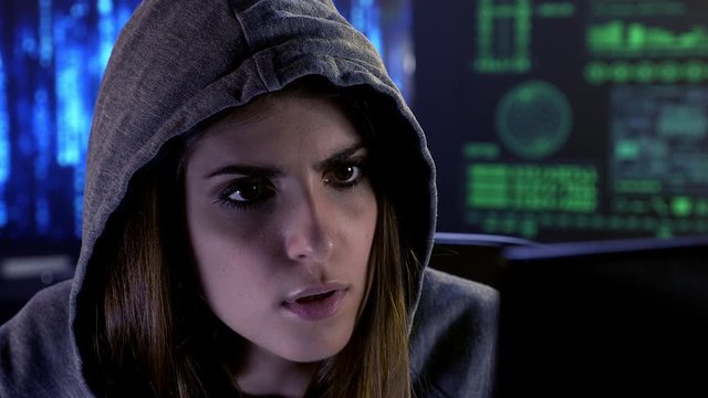 Beautiful female hacker in front of screen concentrated closeup