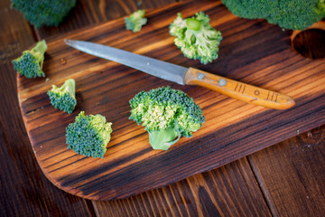 Fresh broccoli cutted on the kitchen board by knife.