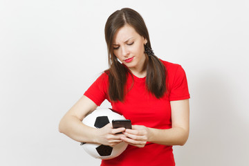 European young angry screaming woman, football fan or player in yellow uniform send sms on mobile phone, hold soccer ball isolated on white background. Sport, play football, healthy lifestyle concept.