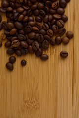 Black coffee grains lie on a brown wooden table, background image