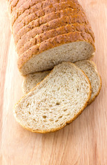 Cutted loaf on a wooden surface. Baton with bran close-up on a wooden board.