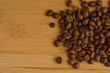 Black coffee grains lie on a brown wooden table, background image