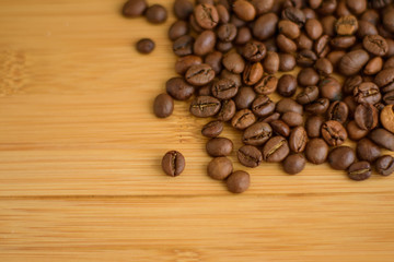 Black coffee grains lie on a brown wooden table, background image