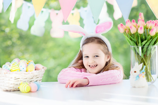 Funny little girl in bunny ears with Easter eggs