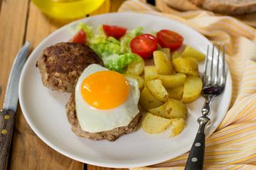 Grilled beef patty meatballs topped with a fried egg with vegetables