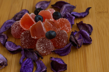Obraz na płótnie Canvas Fruit jelly and petals on a wooden table.