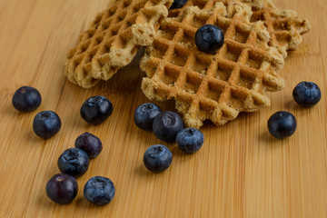 Belgian waffles with fresh berries on cutting board on rustic wooden background