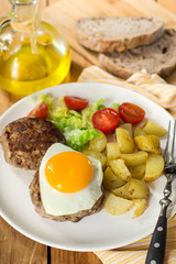 Grilled beef patty meatballs topped with a fried egg with vegetables