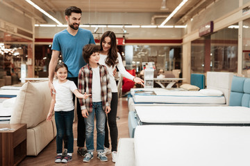 Happy family buys new orthopedic mattress in furniture store. Blissful family choosing mattresses...