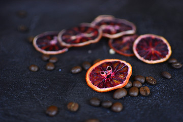 Beautiful and tasty background for design. Dried red orange slices with a coffee beans on a stone background. Cuisine wallpaper.