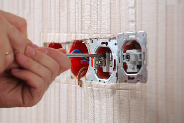 Wall power sockets installation. Male hands with screwdriver installing group of electrical outlets and TV Antenna outlet socket