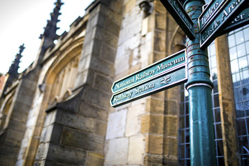 Directional Tourist information and visitor attractions signs to different destinations in the City of York, England, UK with an historic church in the background