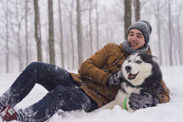 Man walking with dog winter time with snow in forest and siberian husky dog friendship
