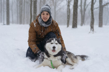 Man walking with dog winter time with snow in forest and siberian husky dog friendship